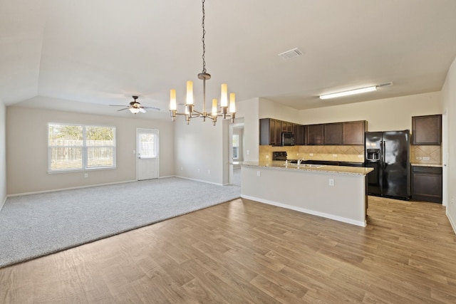 kitchen featuring kitchen peninsula, backsplash, dark brown cabinets, black appliances, and pendant lighting