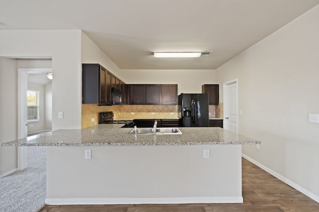 kitchen with black appliances, sink, hardwood / wood-style flooring, tasteful backsplash, and kitchen peninsula