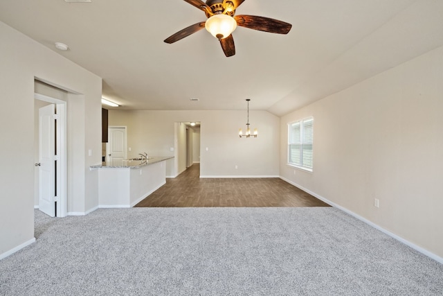 carpeted spare room featuring ceiling fan with notable chandelier and lofted ceiling