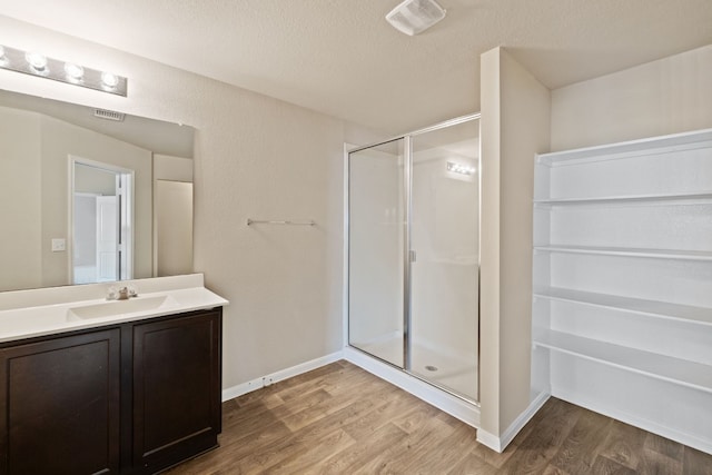 bathroom with hardwood / wood-style floors, vanity, an enclosed shower, and a textured ceiling