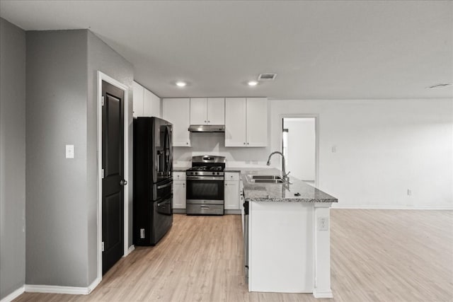 kitchen featuring white cabinetry, stainless steel gas range oven, black fridge, and sink