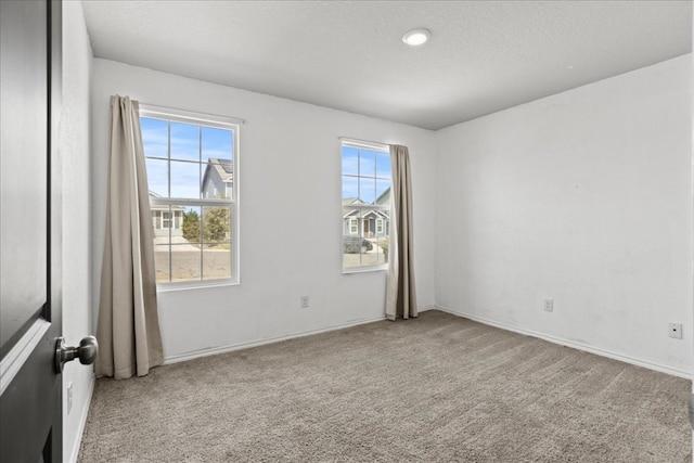 carpeted empty room featuring a textured ceiling