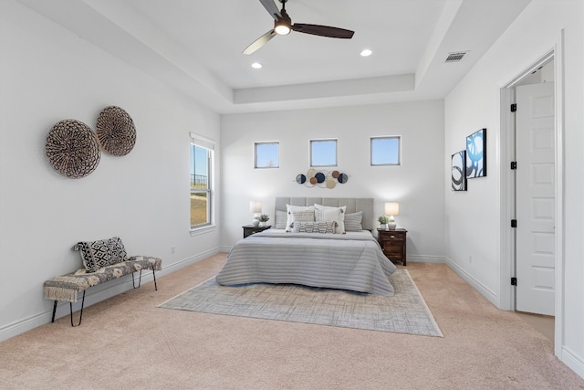 carpeted bedroom featuring a raised ceiling and ceiling fan