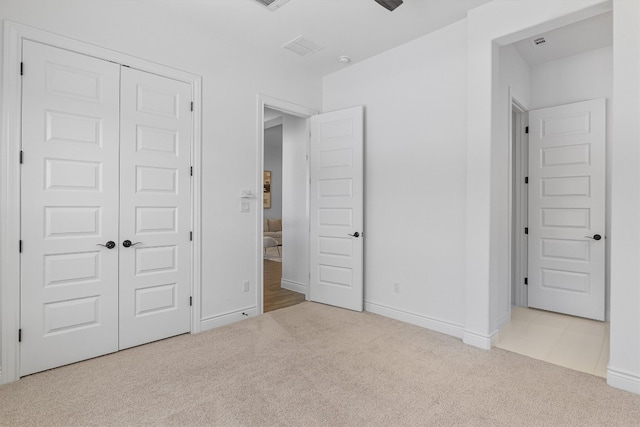 unfurnished bedroom with light colored carpet and a closet