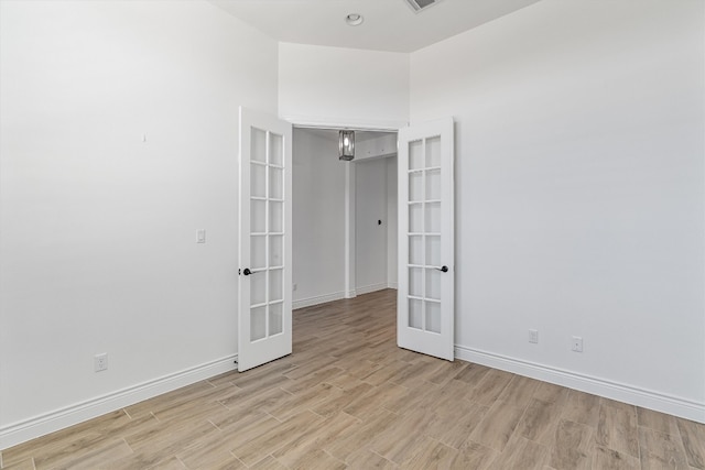 empty room featuring french doors and light wood-type flooring