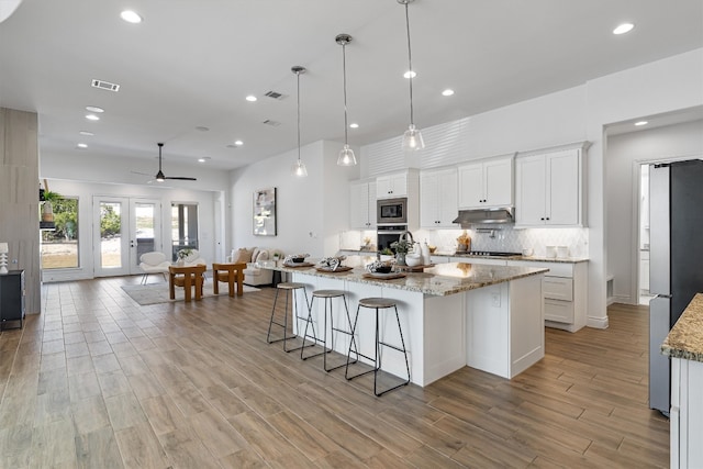 kitchen featuring appliances with stainless steel finishes, ceiling fan, decorative light fixtures, light hardwood / wood-style floors, and white cabinetry