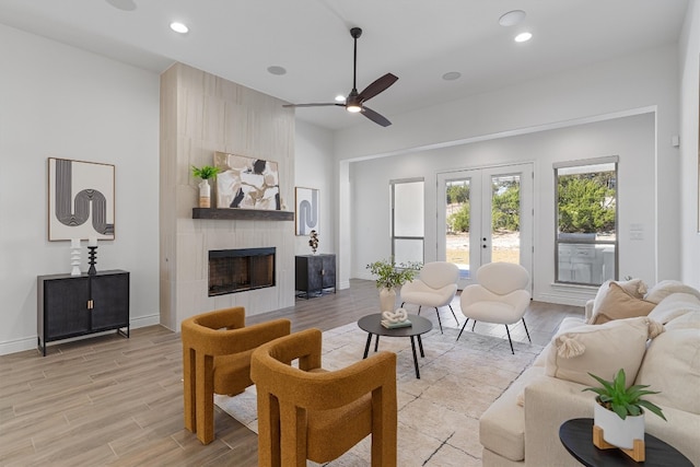 living room featuring a fireplace, ceiling fan, light hardwood / wood-style flooring, and french doors