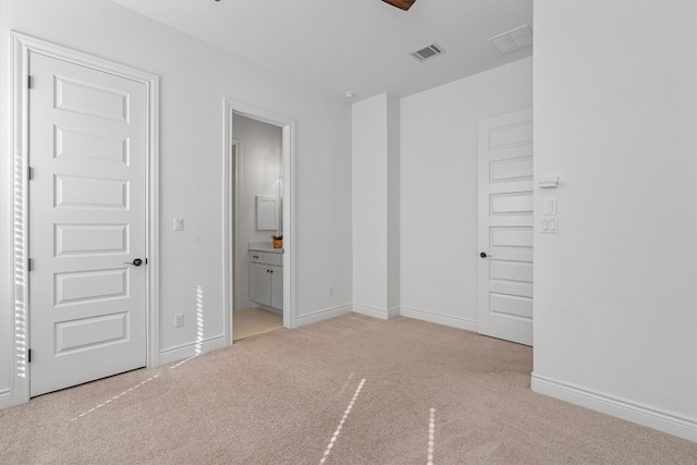 unfurnished bedroom with light carpet and connected bathroom