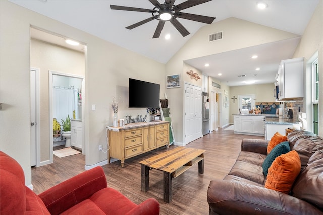 living room with ceiling fan, vaulted ceiling, and hardwood / wood-style flooring