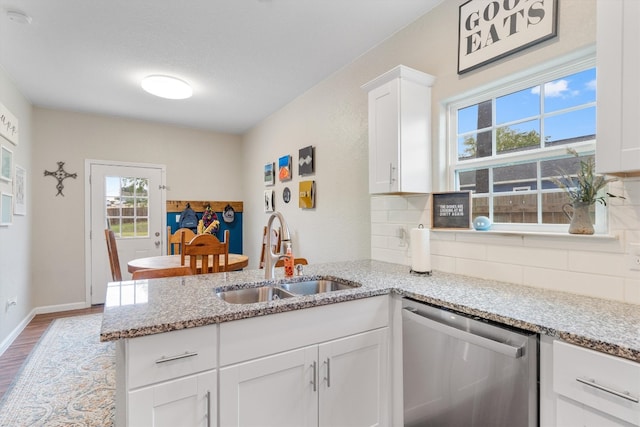 kitchen with dishwasher, sink, light hardwood / wood-style floors, light stone counters, and white cabinetry