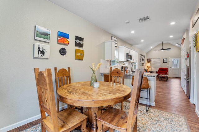 dining space featuring ceiling fan, hardwood / wood-style floors, lofted ceiling, and sink