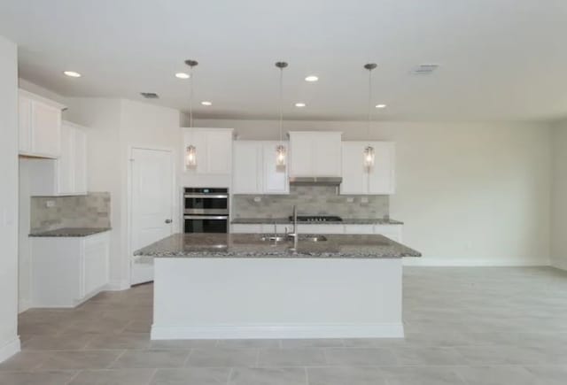 kitchen with white cabinetry, a center island with sink, and decorative light fixtures