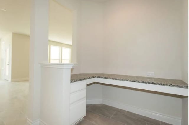 unfurnished office featuring tile patterned floors and built in desk