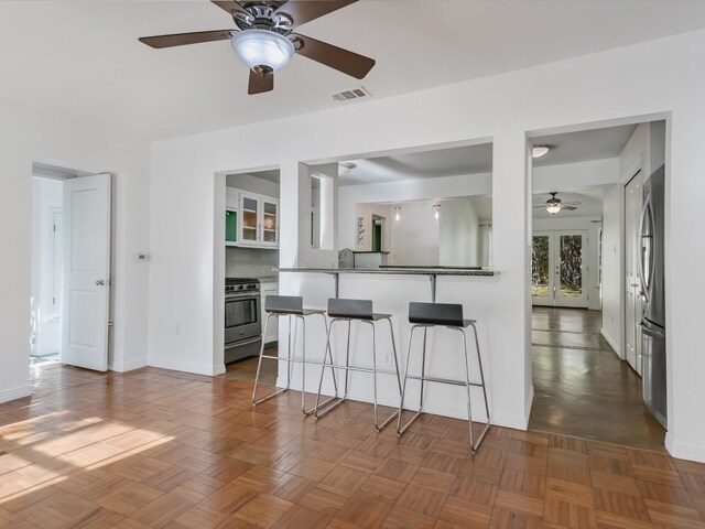 kitchen with kitchen peninsula, appliances with stainless steel finishes, french doors, a kitchen breakfast bar, and sink