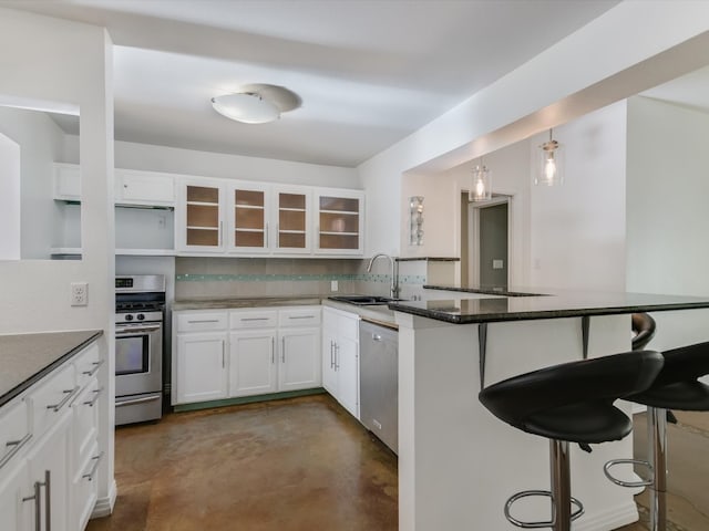 kitchen with a kitchen bar, appliances with stainless steel finishes, backsplash, sink, and white cabinets