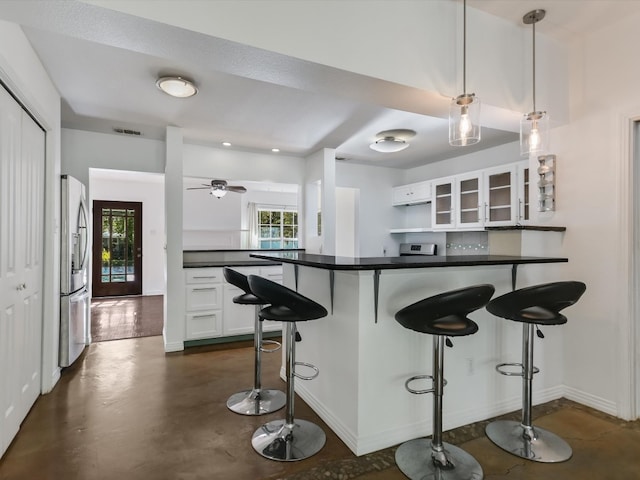 kitchen featuring white cabinets, stainless steel refrigerator with ice dispenser, a kitchen bar, and pendant lighting