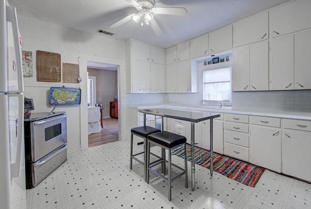 kitchen with ceiling fan, white cabinets, white fridge, and stainless steel range with electric cooktop