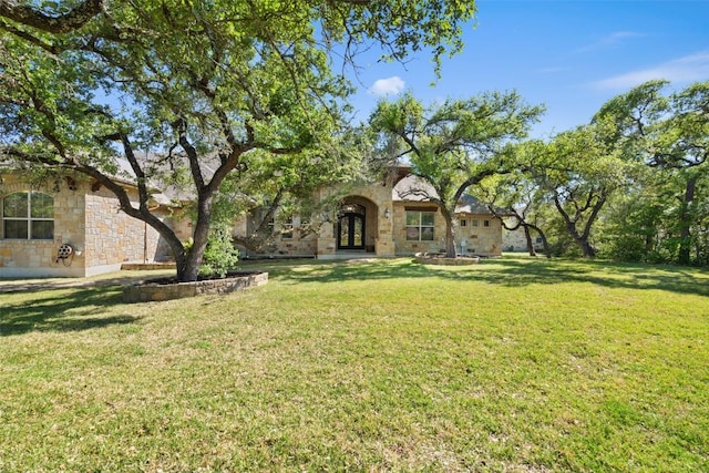 view of front of home with stone siding, a front yard, and french doors