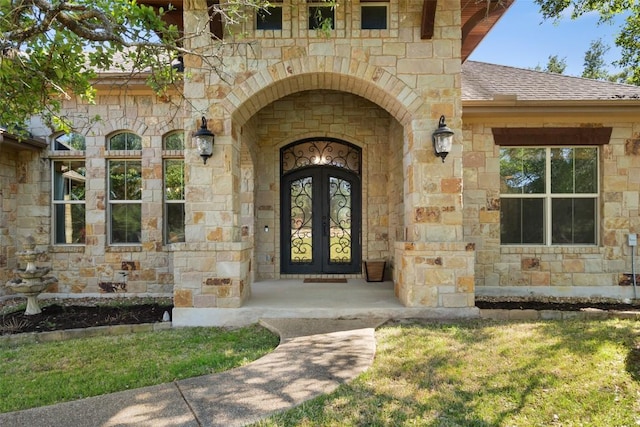 property entrance with stone siding, french doors, and a shingled roof