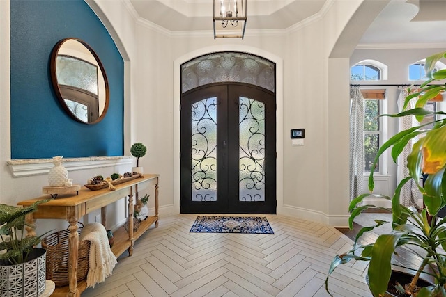 foyer featuring ornamental molding, arched walkways, french doors, and baseboards