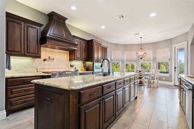 kitchen with premium range hood, stainless steel gas stovetop, tasteful backsplash, and dark brown cabinets