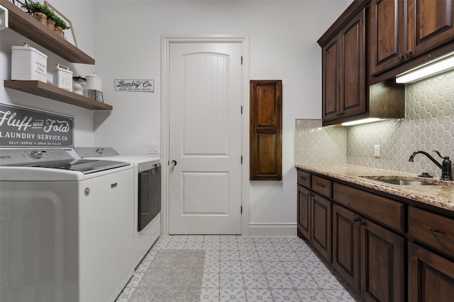 laundry room featuring cabinet space, baseboards, a sink, and washing machine and clothes dryer