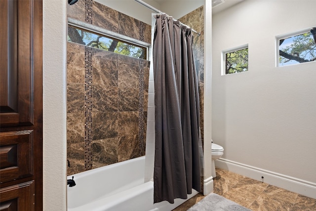 bathroom featuring toilet, baseboards, and shower / tub combo with curtain