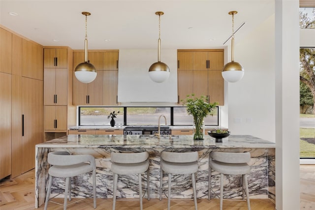 kitchen featuring hanging light fixtures, light parquet flooring, stove, and light stone counters