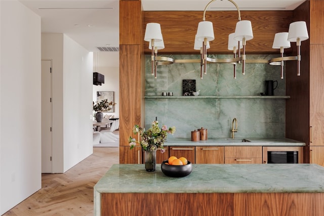 kitchen with wine cooler, sink, light stone countertops, and light parquet floors