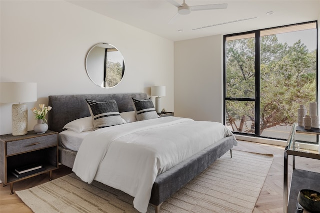 bedroom with ceiling fan, a wall of windows, and light parquet floors