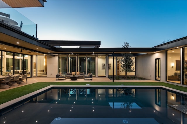 pool at dusk featuring outdoor lounge area and a patio