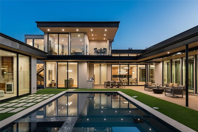 back house at dusk with a pool with hot tub, an outdoor living space, and a patio area