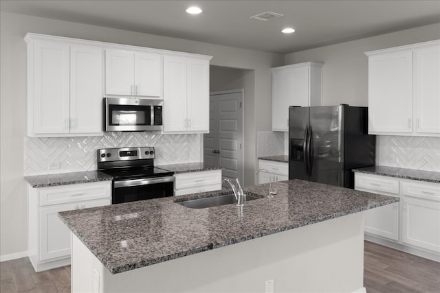 kitchen with light wood-type flooring, sink, appliances with stainless steel finishes, and an island with sink