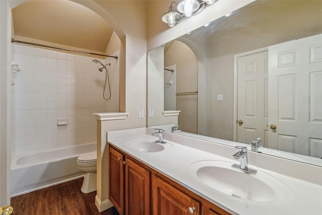 full bathroom featuring toilet, tiled shower / bath, vanity, and hardwood / wood-style floors