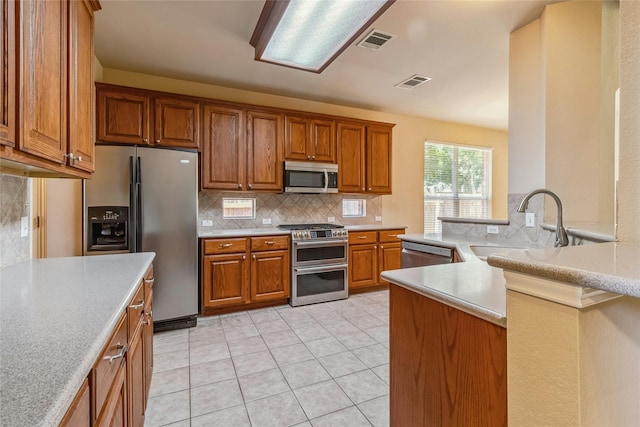 kitchen with sink, decorative backsplash, light tile patterned floors, and appliances with stainless steel finishes