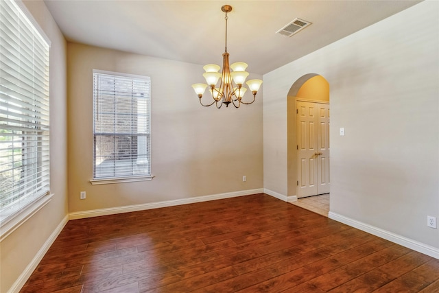 empty room featuring an inviting chandelier and hardwood / wood-style flooring