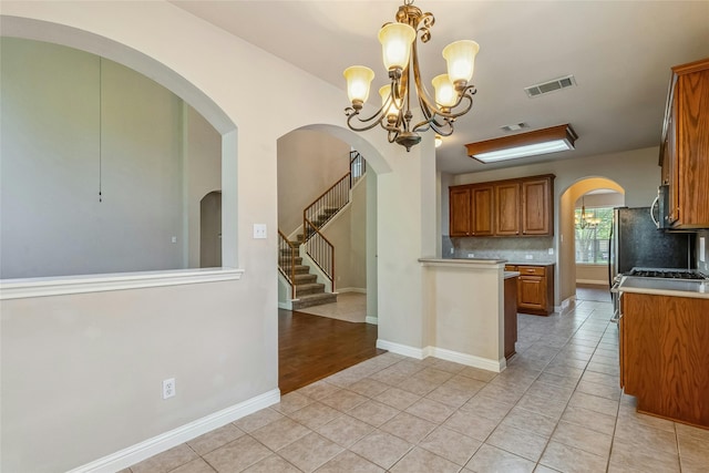 kitchen with decorative light fixtures, light tile patterned flooring, decorative backsplash, and an inviting chandelier