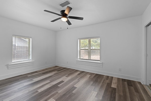 empty room featuring dark hardwood / wood-style flooring, plenty of natural light, and ceiling fan