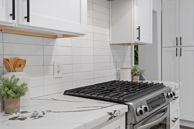 kitchen with decorative backsplash, white cabinetry, light stone countertops, and stainless steel range with gas cooktop