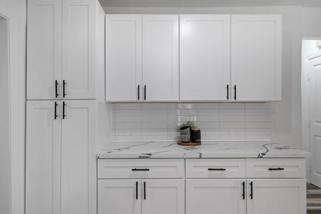 bar with white cabinets, decorative backsplash, light stone countertops, and wood-type flooring