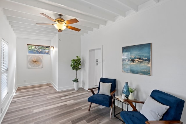 sitting room with ceiling fan, light hardwood / wood-style flooring, and beamed ceiling