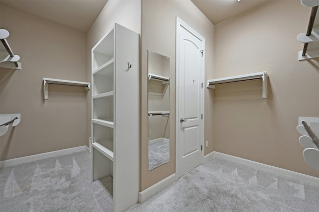 walk in closet featuring light colored carpet