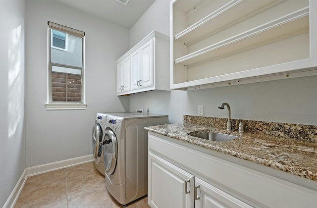 washroom with sink, light tile patterned floors, cabinets, and washing machine and clothes dryer