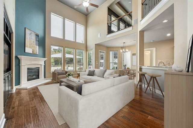 living room featuring ceiling fan with notable chandelier and dark hardwood / wood-style floors