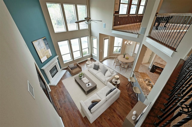 living room featuring dark hardwood / wood-style flooring, sink, ceiling fan with notable chandelier, and a high ceiling