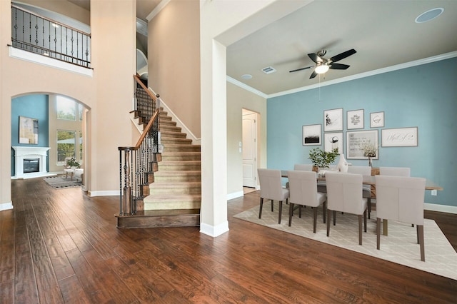 dining room featuring dark hardwood / wood-style flooring, crown molding, ceiling fan, and a high ceiling