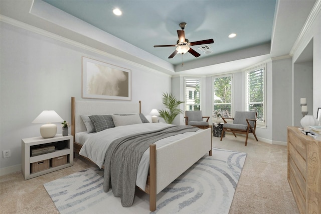 bedroom with crown molding, light colored carpet, and a raised ceiling