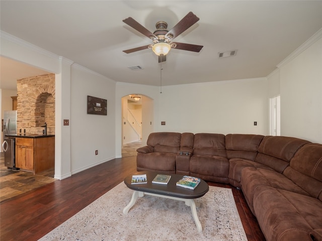 living room featuring ceiling fan, ornamental molding, and dark wood-type flooring