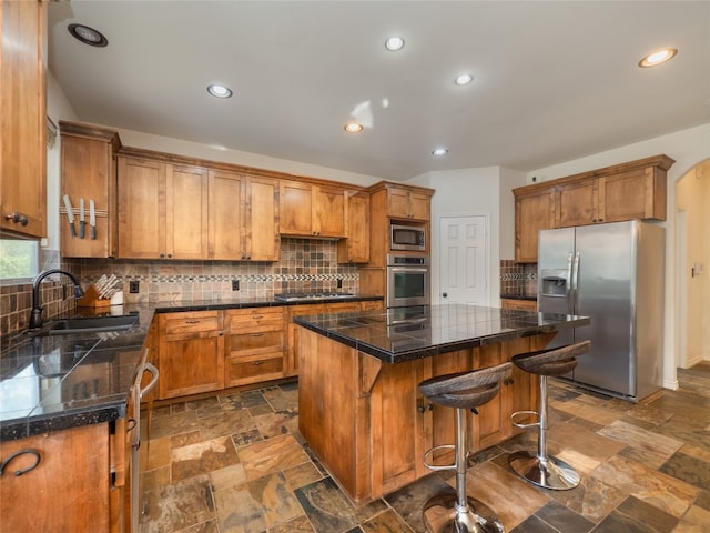 kitchen featuring a kitchen breakfast bar, sink, appliances with stainless steel finishes, tasteful backsplash, and a kitchen island