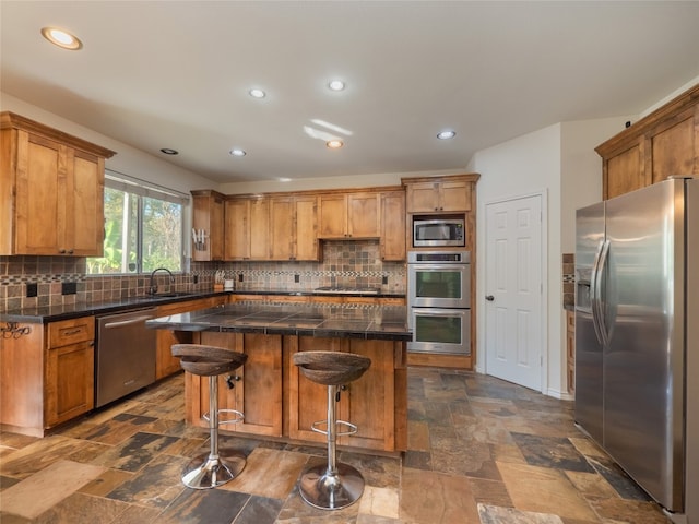 kitchen with a breakfast bar, appliances with stainless steel finishes, tasteful backsplash, and a kitchen island